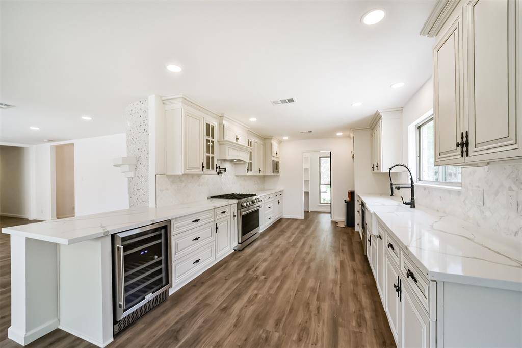 This gorgeous galley kitchen features quartz countertops, a wine fridge, 36" gas range stove, pot filler, remote controlled hood, and a huge walk-in pantry with pocket door access
