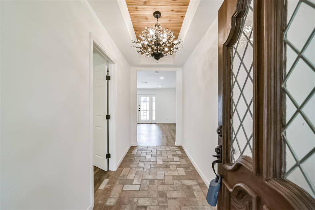 Welcome home! Beautiful chandelier, custom wood worked tray ceiling and brick tiled floor greet you in this gorgeous front entryway.