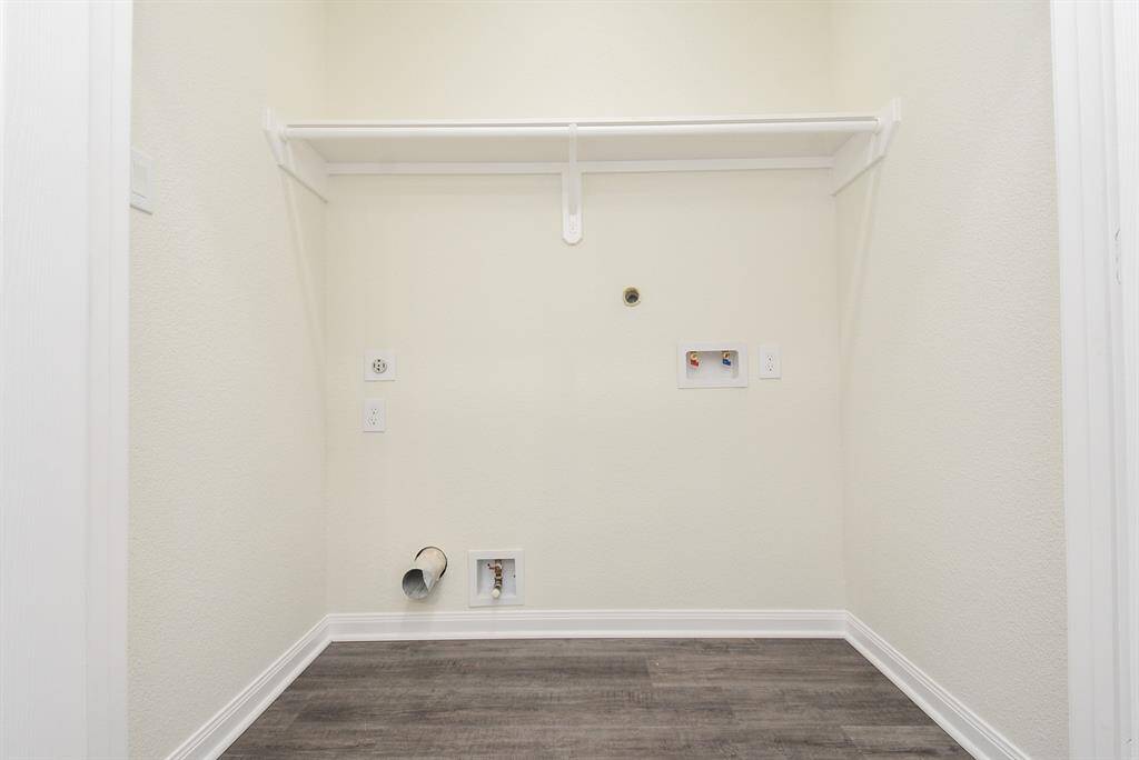 An empty closet with a shelf, clothes rod, and various wall outlets and connections.