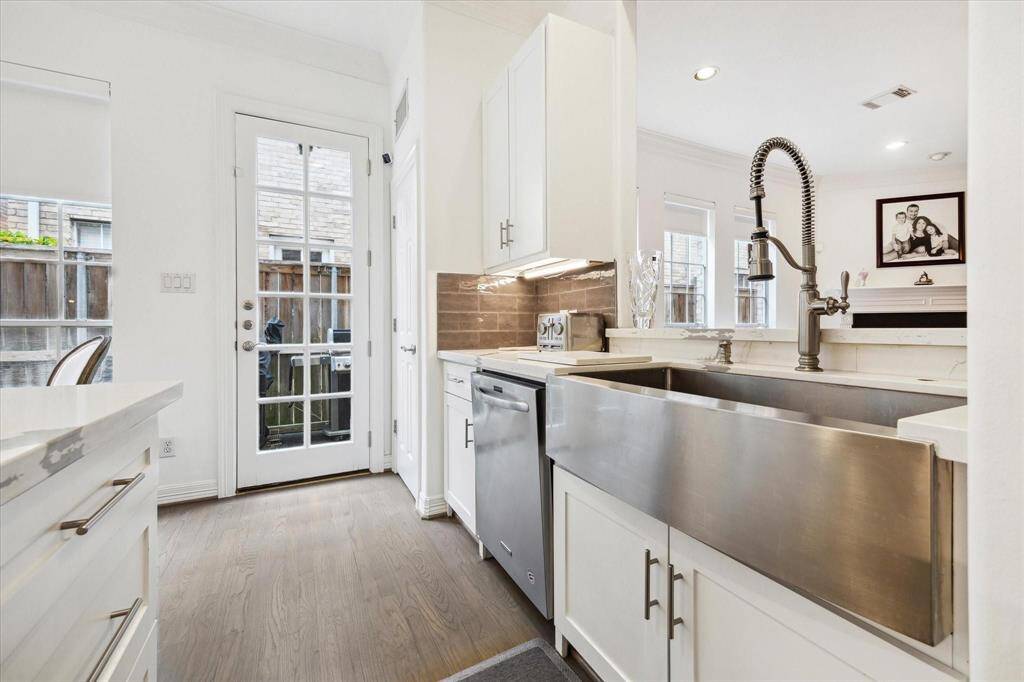 Sleek modern kitchen featuring a deep stainless steel sink, updated fixtures, and backyard views through large windows that bring in abundant natural light.