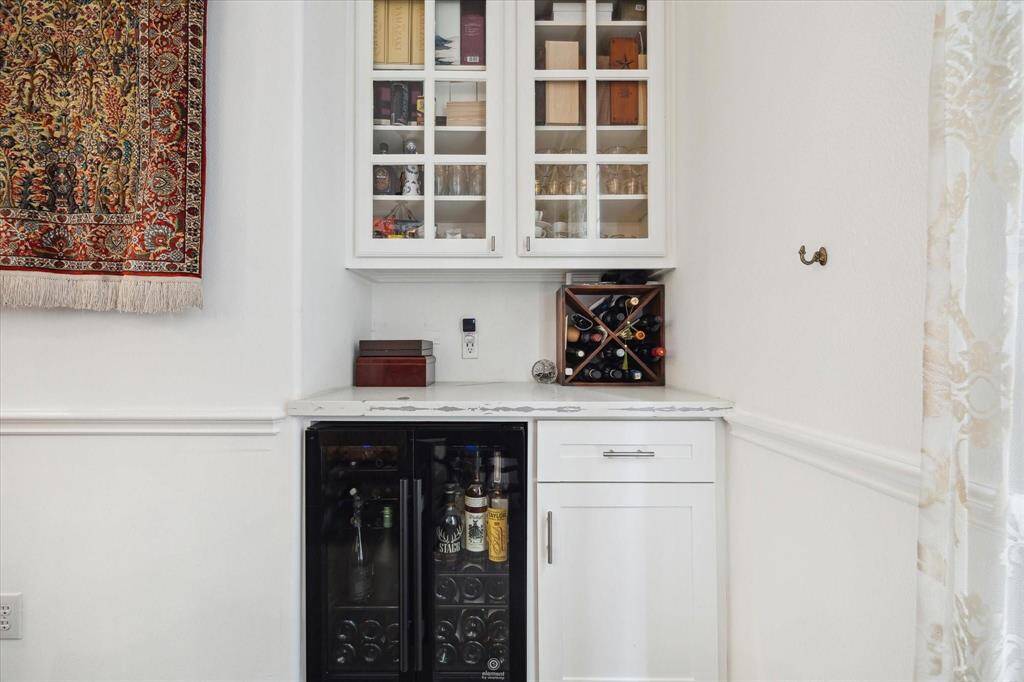 Chic built-in wine bar with glass-front cabinetry and a beverage fridge—ideal for hosting or winding down in style.