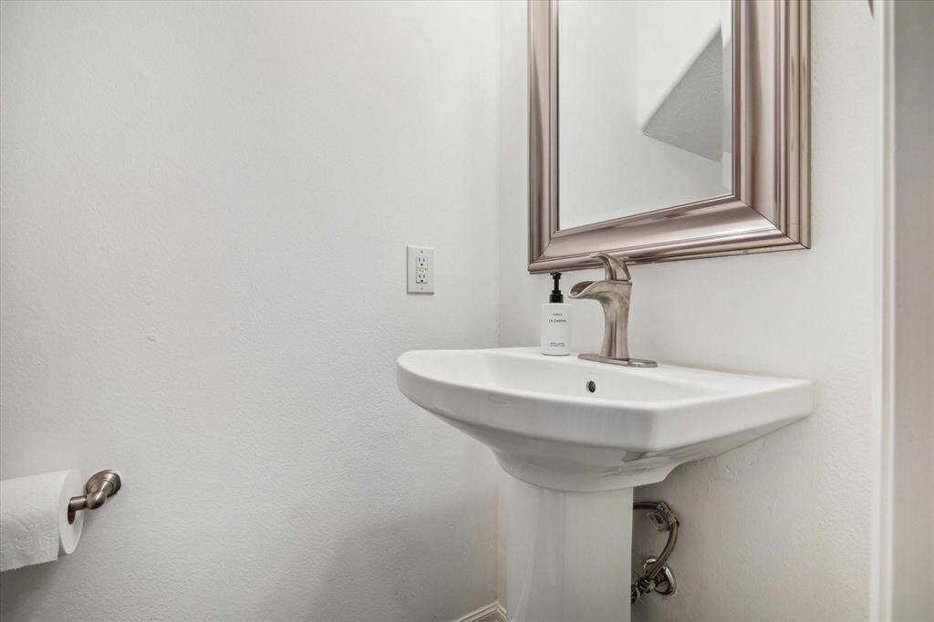 Clean and elegant powder bath with a pedestal sink and framed mirror, perfect for guests.