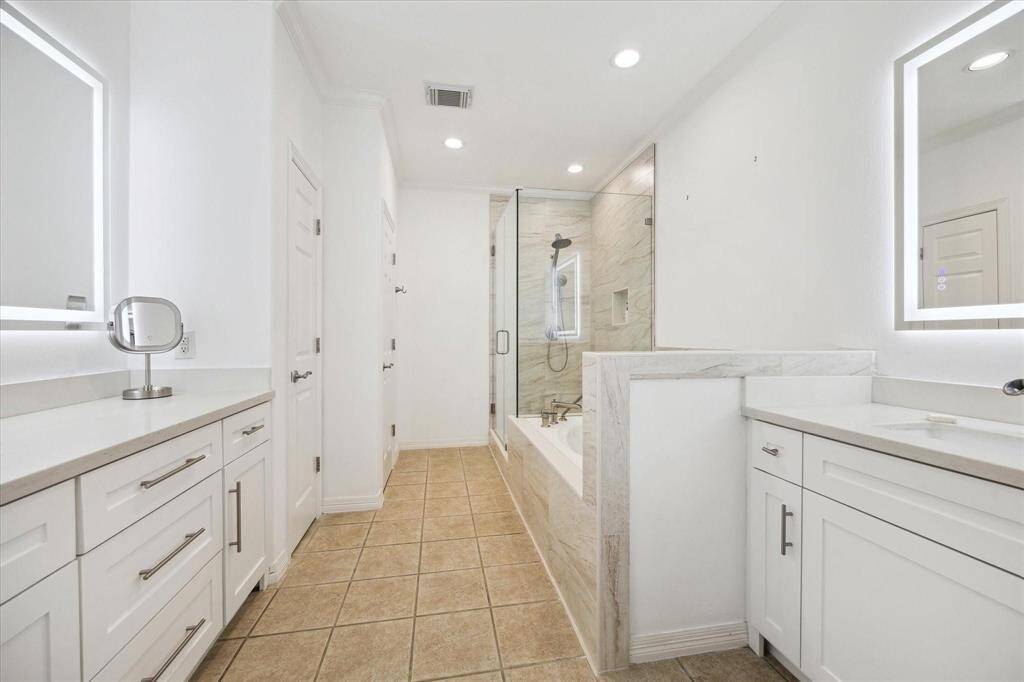 Luxurious primary bath featuring dual vanities, a walk-in shower, and modern lighting for a spa-like experience.