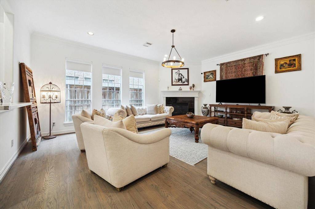 Spacious and bright living room featuring large windows, wood flooring, and an open layout perfect for relaxing or entertaining.