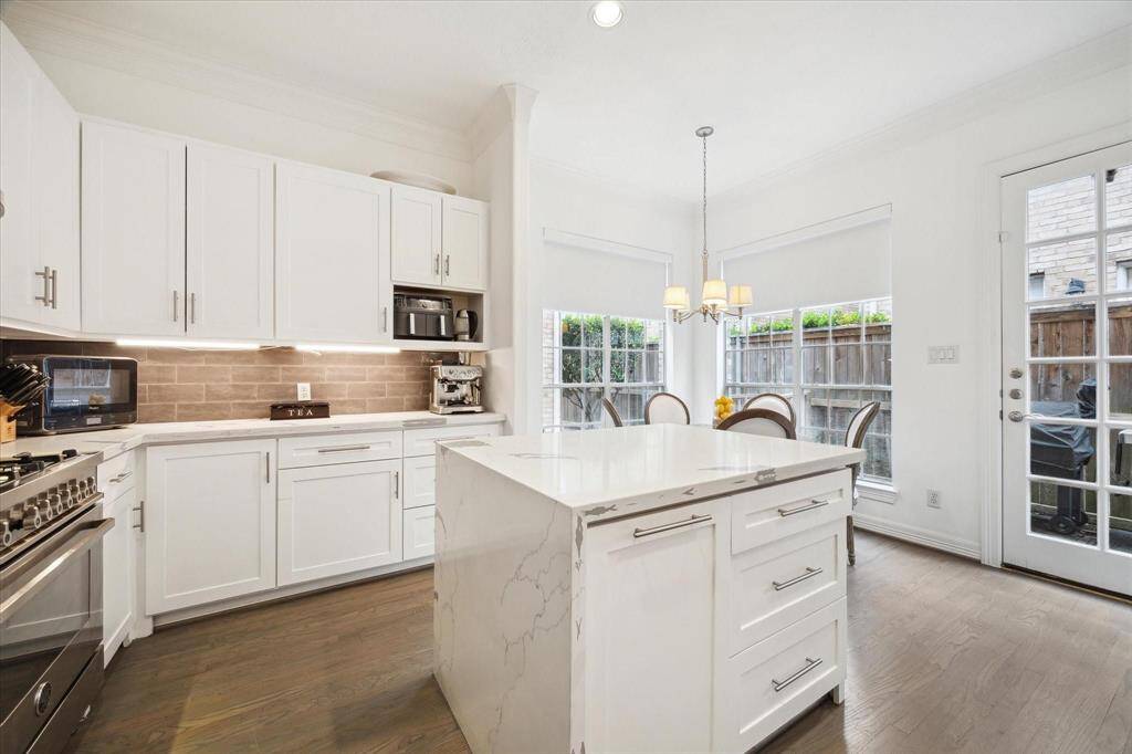 Upgraded kitchen with white cabinetry, granite countertops, stainless steel appliances, and a functional center island for prepping or gathering