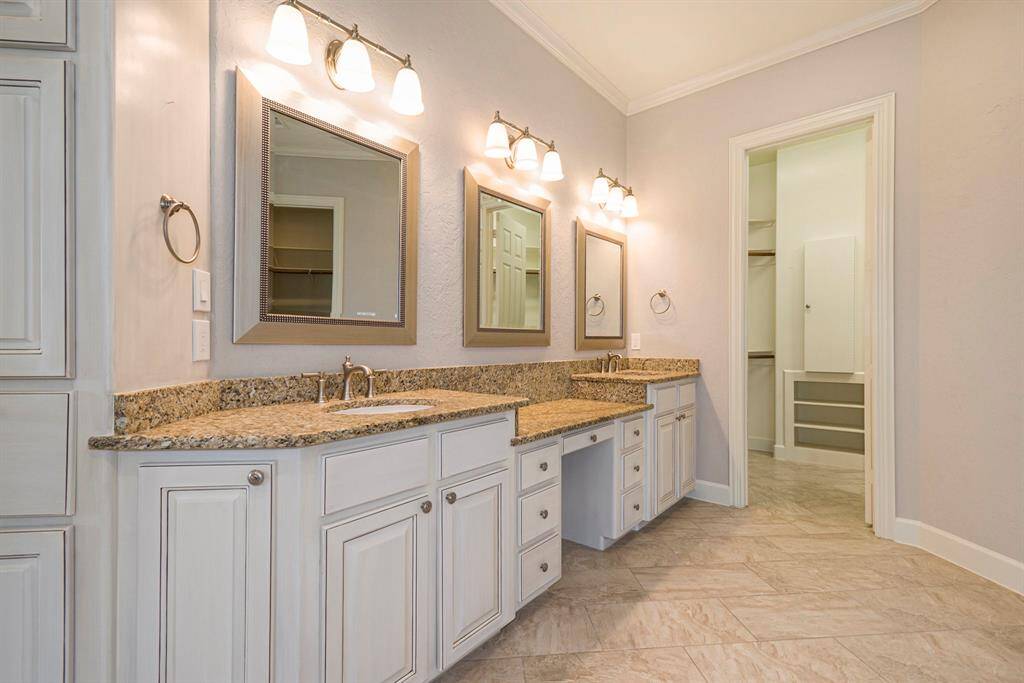 Primary bath features dual sinks, vanity, linen cabinet and 2 walk in closets with built in shelving/drawers