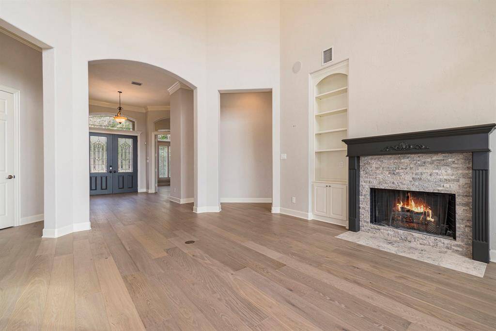 The formal Sitting/Living room features high ceilings, fireplace, built in shelving & speakers