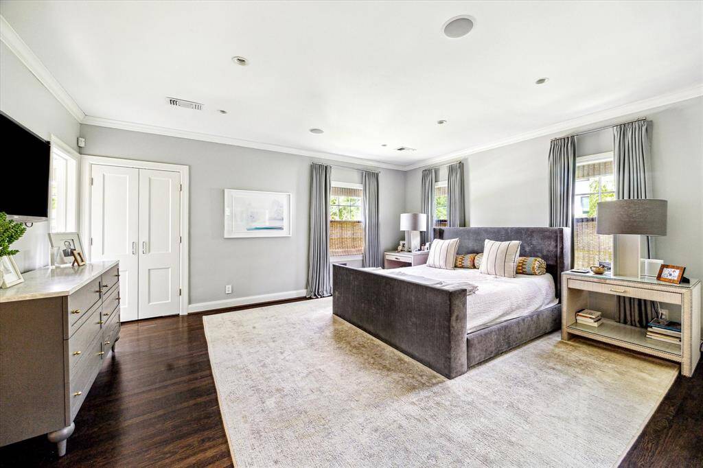Sophisticated and spacious, the primary bedroom is a true retreat featuring hardwood floors, soft natural light, and serene gray tones throughout. Thoughtfully designed with multiple windows and ample wall space, it balances comfort and elegance effortlessly.