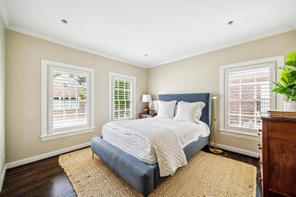 This light-filled secondary bedroom offers a peaceful retreat with hardwood floors, crown molding, and classic plantation shutters. Thoughtfully designed for comfort, it’s a versatile space ideal for guests or family.