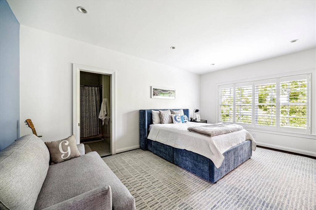 Bright and spacious, this secondary bedroom features wide-plank hardwood floors, generous natural light, and an en suite bath for added convenience. Plantation shutters and a soft color palette create a calm, comfortable atmosphere.