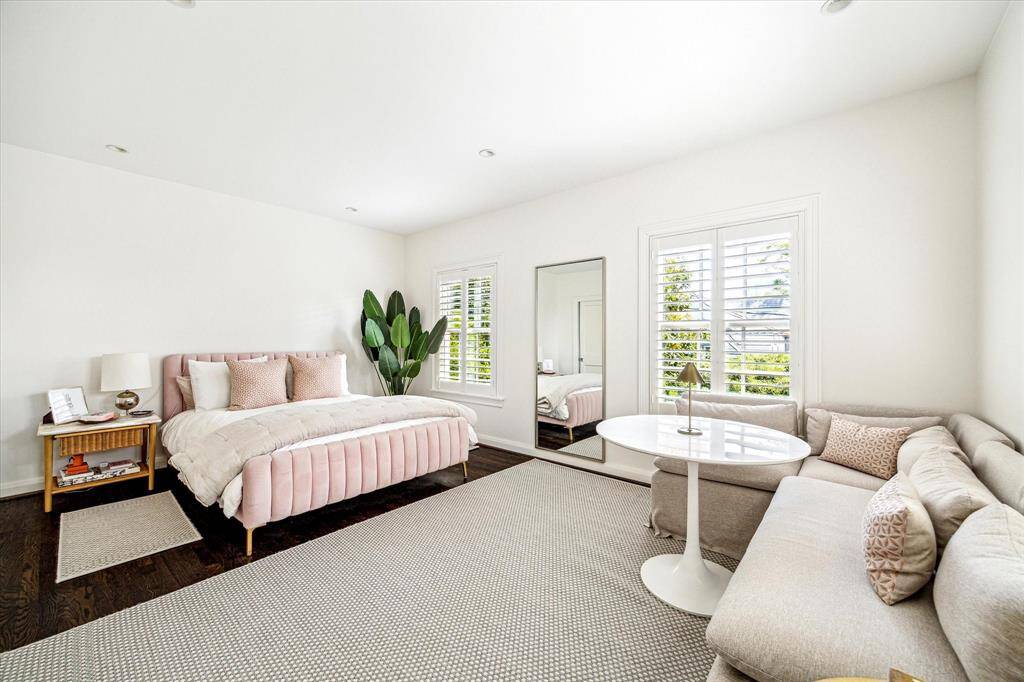Generously sized and filled with natural light, this secondary bedroom offers the flexibility to accommodate both sleep and lounge areas. Plantation shutters, hardwood floors, and a clean, neutral palette make it a bright and inviting retreat.