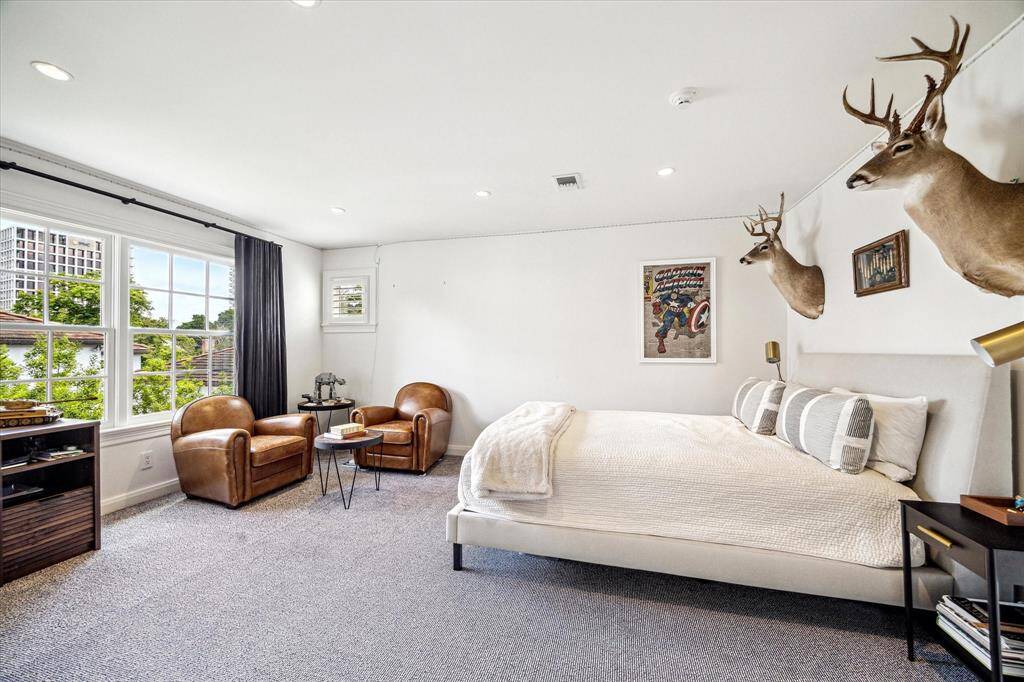 Expansive and light-filled, this secondary bedroom offers ample space for both relaxation and study. Large windows frame treetop views, while neutral tones and plush carpeting create a comfortable and versatile retreat.