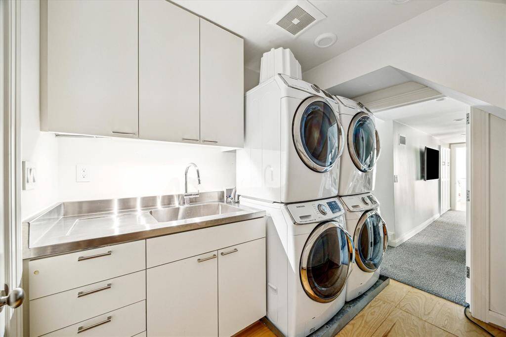 Efficient and well-appointed, the laundry room features dual washer-dryer sets, a stainless steel utility sink, and ample built-in cabinetry for storage. Bright and functional, it’s designed to handle household tasks with ease.