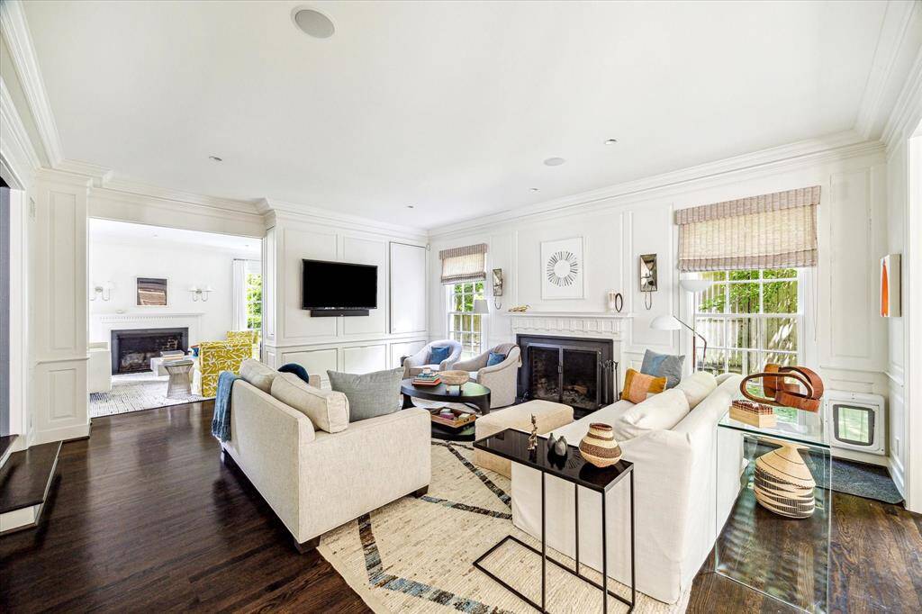 The family room exudes warmth and sophistication with rich hardwood floors, detailed wall paneling, and a stately fireplace as its focal point. Abundant natural light and seamless flow to the formal living room make this an inviting space for everyday living and entertaining.