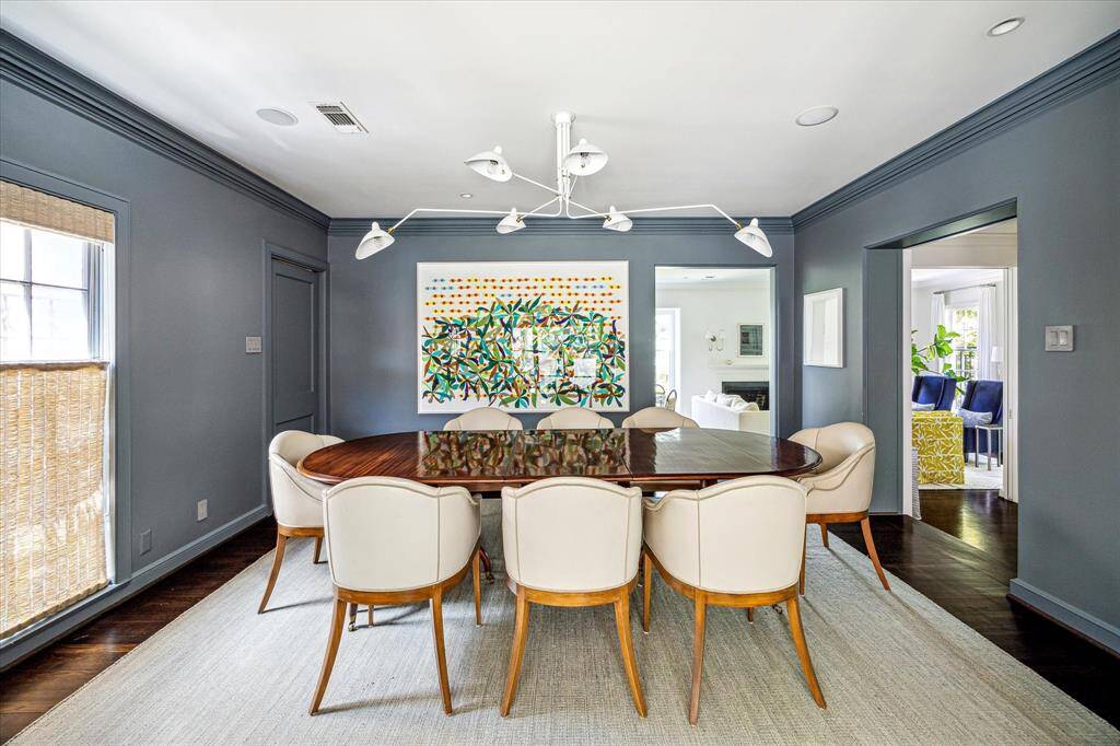 The dining room makes a statement with its bold wall color, elegant crown molding, and gleaming hardwood floors—all anchored by a striking Serge Mouille pendant lamp. Ideally situated between the living and family rooms, it offers a seamless flow for both formal entertaining and intimate gatherings.