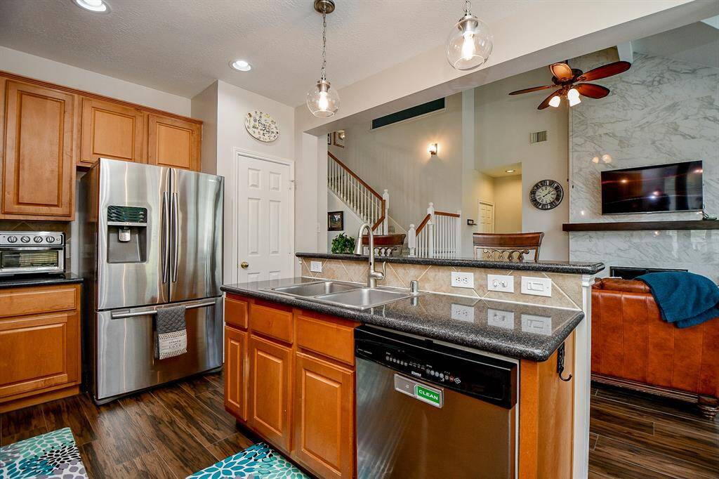 Honey toned cabinetry fills every inch of wall/floor space, both up and down in this lovely, truly workable kitchen. Deep granite counter tops sit below warm, earth toned tile backsplash. The elevated, extended counter easily invites comfy stools.