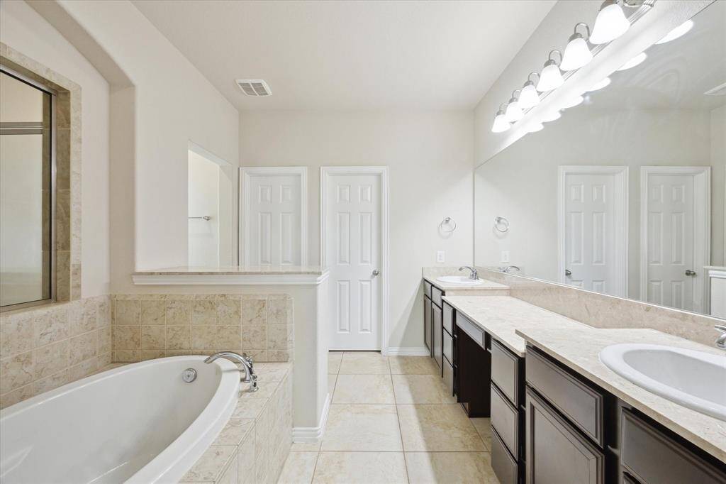 Primary Bath features a large tub, oversized shower, double sinks, vanity space, water closet and large walk in closet. Tile flooring, neutral colors and lots of storage.