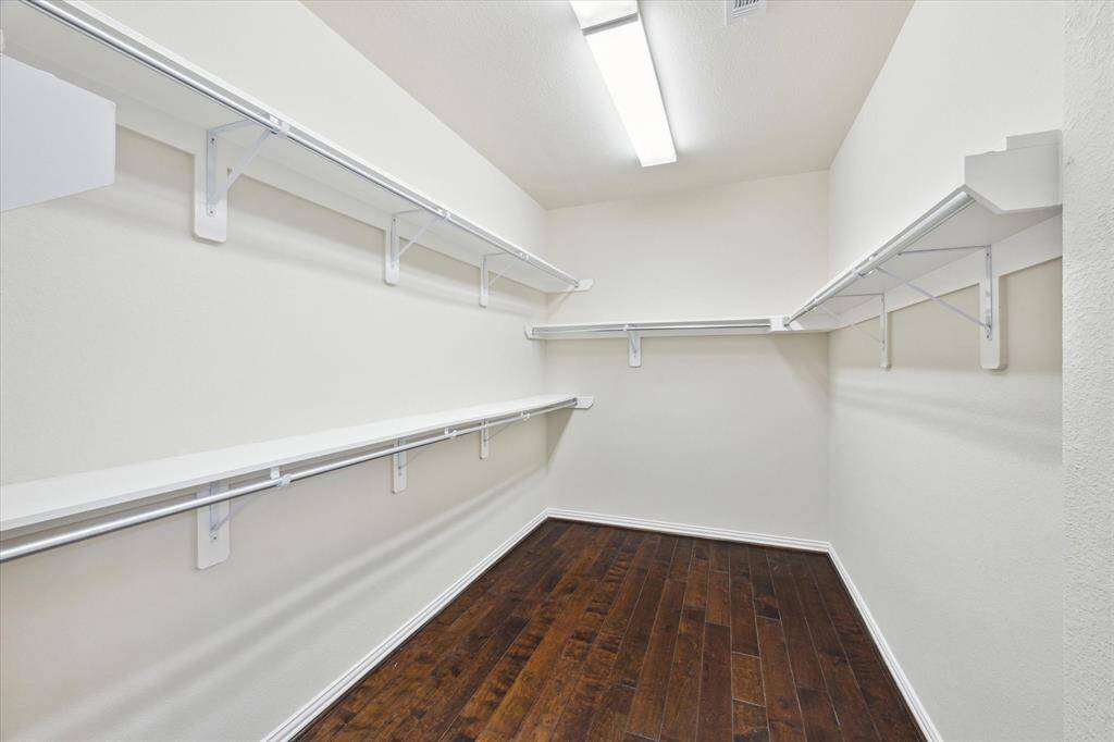 Primary closet! Shelving, double hanging space, and hardwood flooring.