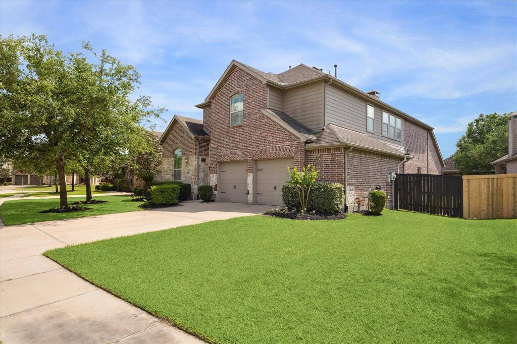 Another view of the front elevation with detailed brickwork and stone accents. Fresh landscaping and seasonal planting is a welcoming first impression.