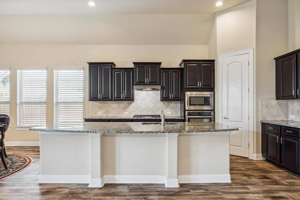 Experience the elegance of this gourmet kitchen featuring an eat-in island, 42" cabinets with crown molding, granite countertops, stainless steel appliances, and a walk-in pantry, all seamlessly connected to the family room.