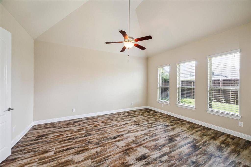 Spacious primary bedroom with high ceilings and stylish wood-look tile flooring.