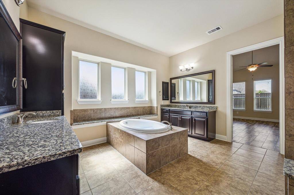 Experience luxury in the owner's suite with an elegant en-suite bath, featuring dual vanities, a soaking tub, and a spacious custom walk-in closet.