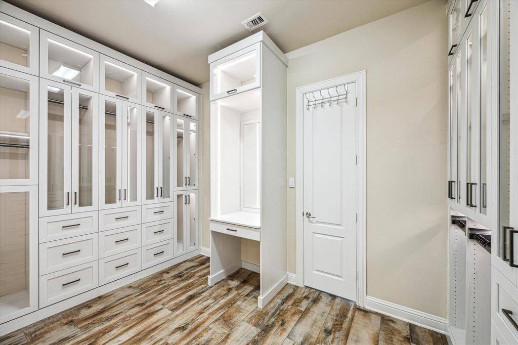 Elegant en-suite closet featuring a vanity nook, mirror, and stylish wood-look tile flooring.