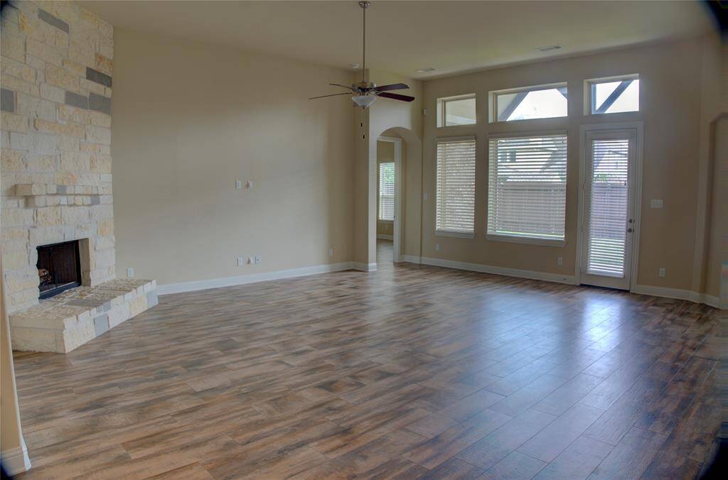 Discover elegance with high ceilings and graceful arches. The spacious family room features a stunning stone fireplace and chic wood-like flooring.