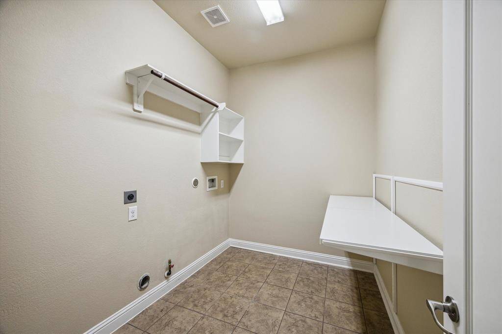 Experience the convenience of a spacious laundry room with ample shelving and a custom counter for easy folding and ironing.