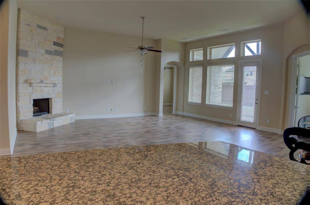 Experience elegance with high ceilings and graceful arches. The spacious family room boasts a stunning stone fireplace and sleek wood-like flooring.