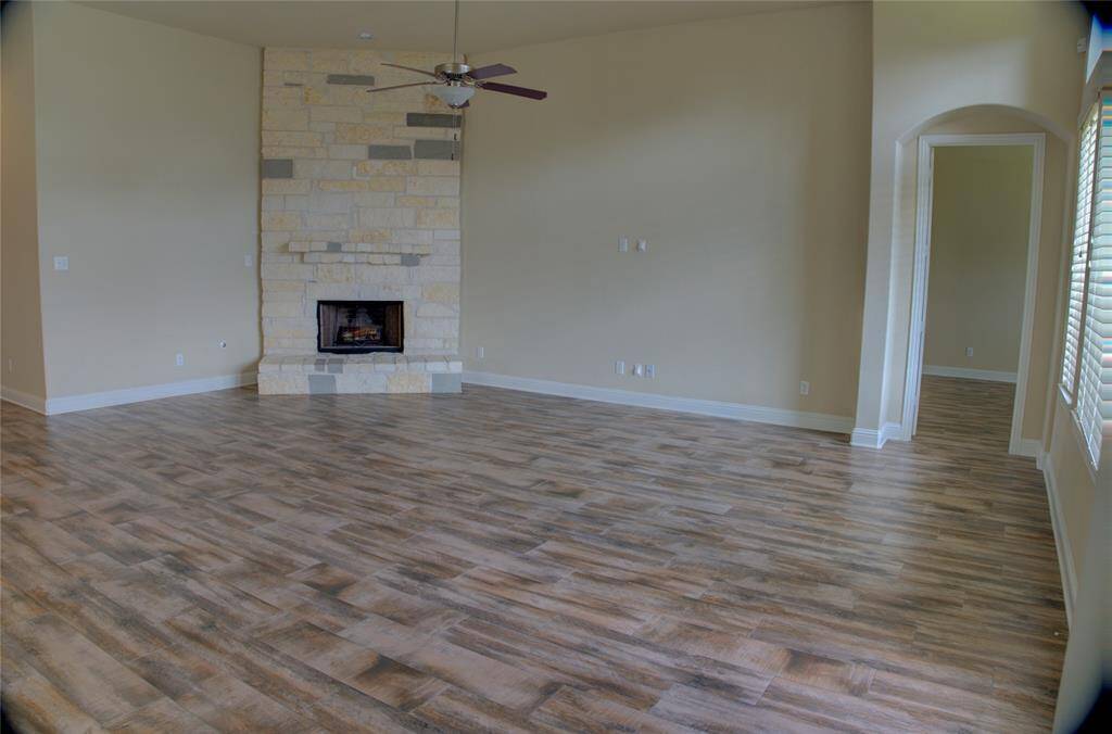 Cozy family room featuring elegant wood-like flooring and a captivating stone fireplace.