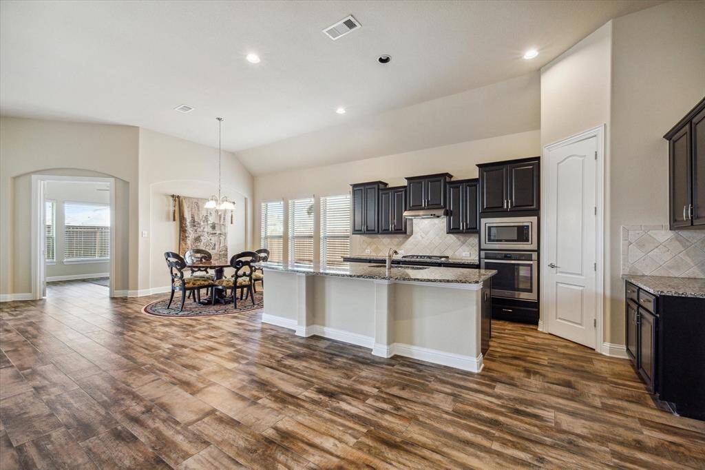 Expansive chef's kitchen with an island, seamlessly connecting to a sunlit breakfast area.