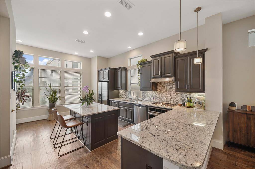 Stunning kitchen with sleek lines, granite counters, stainless appliances, stylish pendant lights and gas cook-top.