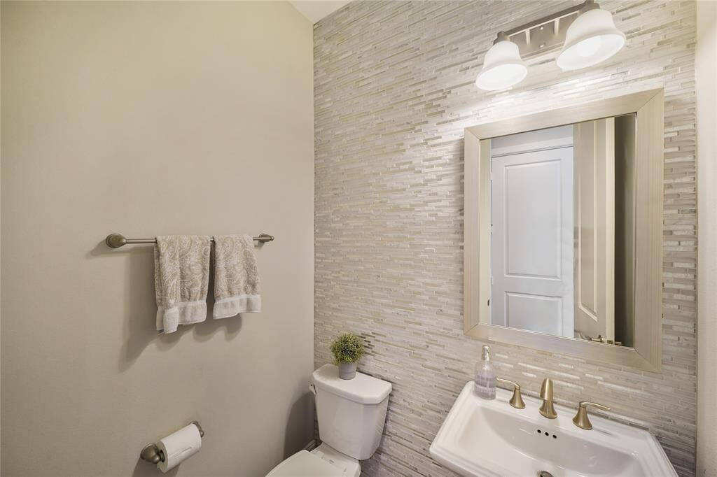Nicely appointed half bath with floor to ceiling tile.