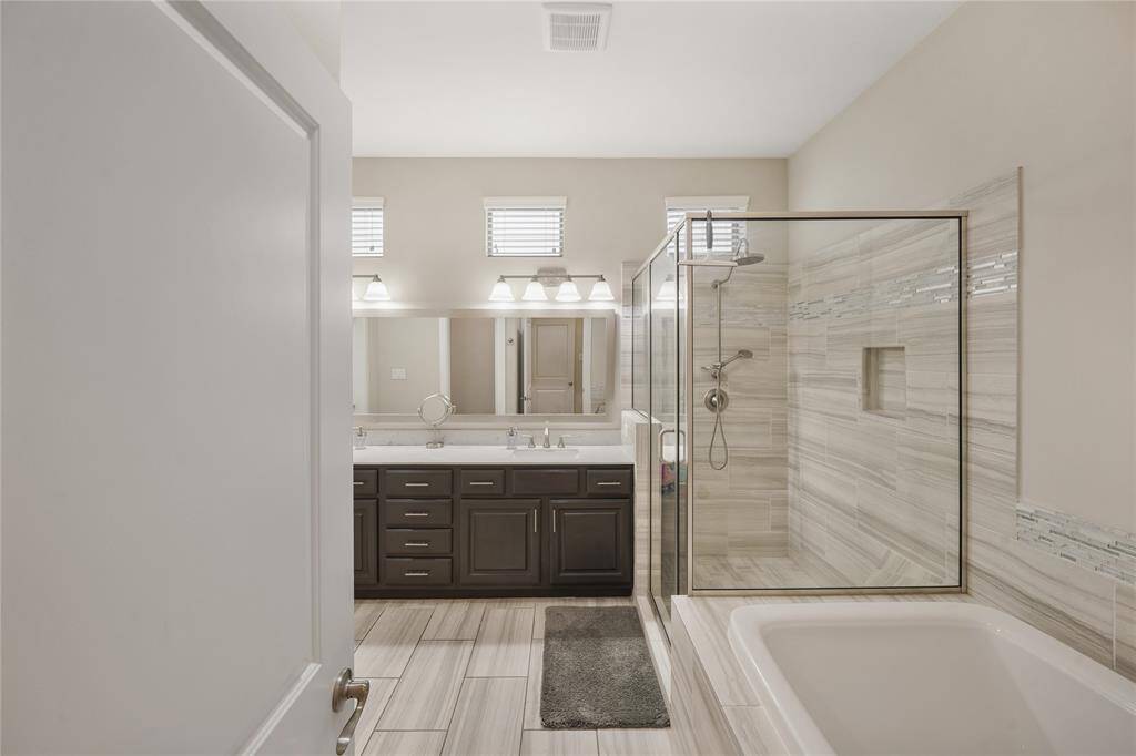 Luxurious primary bath featuring a separate tub and glass-enclosed shower.