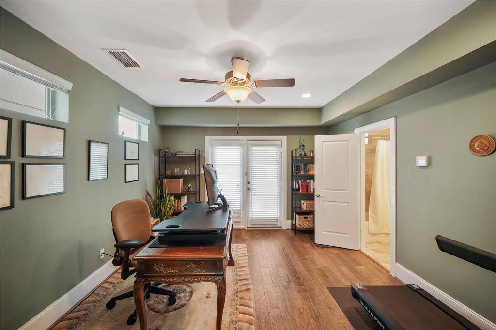 Spacious downstairs bedroom featuring wood flooring, a ceiling fan, and an en suite bathroom.
