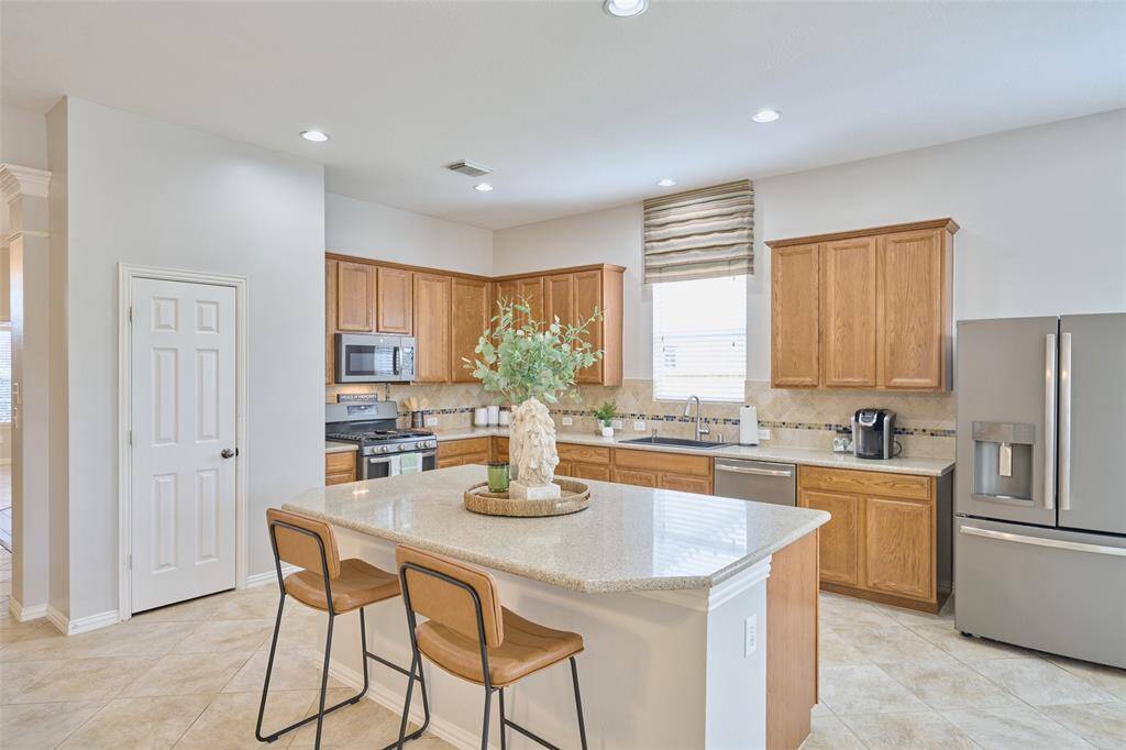 The kitchen features ample cabinet and counter space, along with an oversized island. The refrigerator is included in the sale of the home.