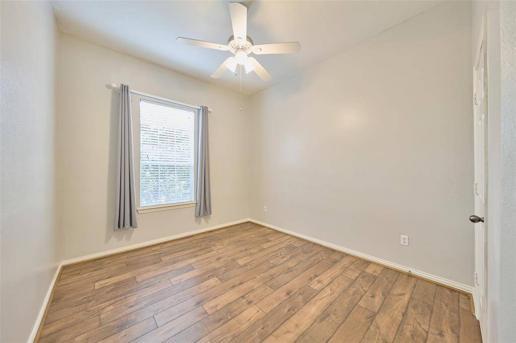 Generous secondary bedroom featuring luxury vinyl plank flooring and a ceiling fan.