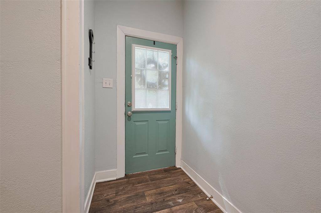 Step into a warm and inviting entryway, featuring a charming front door with a window, soft-toned walls, and wood-look floors that add rustic elegance.
