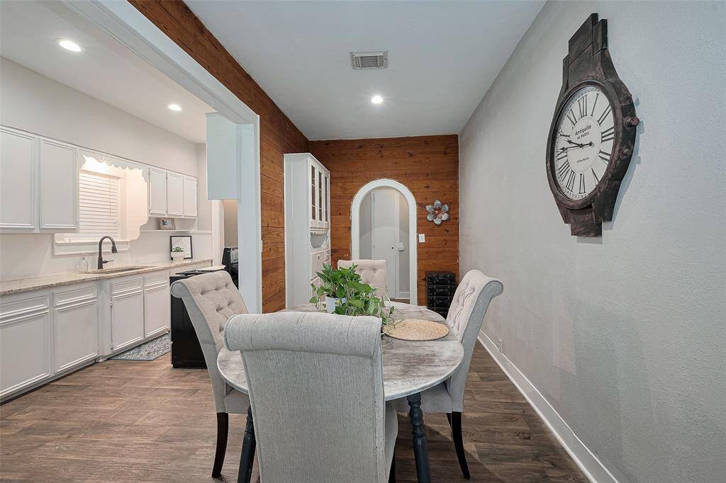 This photo features a cozy dining area with wood paneling to add warmth to the space. The adjacent kitchen has white cabinetry and a modern faucet, offering a clean, inviting space.