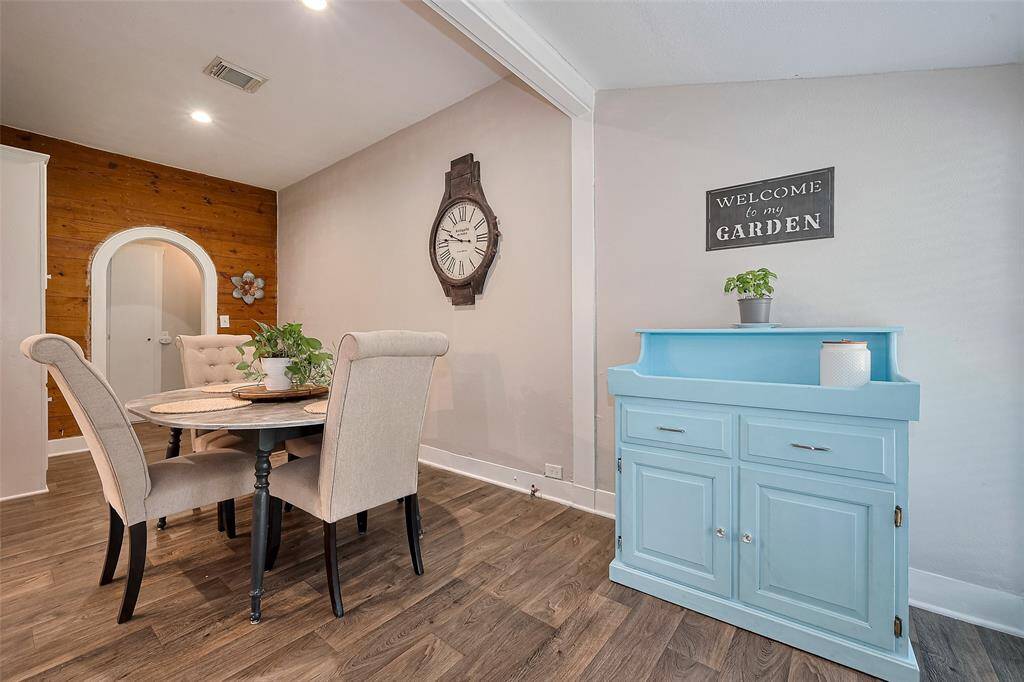 This cozy dining area and kitchen features a rustic wood accent wall, built-in white cabinetry, and modern appliances—blending farmhouse warmth with everyday functionality.