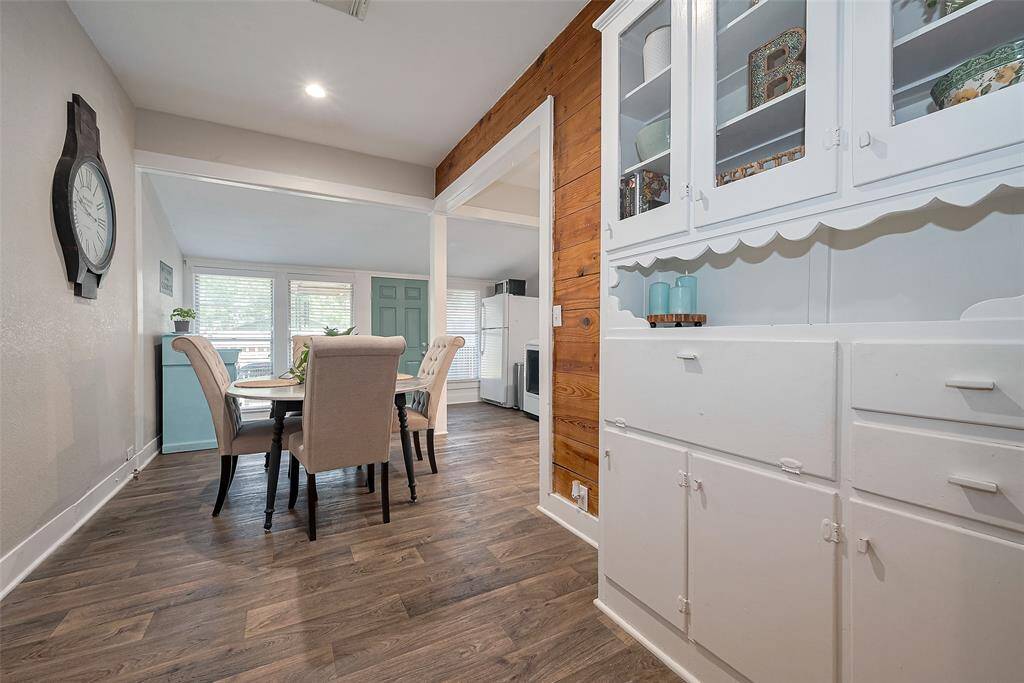 This photo showcases a bright, open dining area with wood-look flooring and a built-in white cabinet for added storage. Large windows fill the space with natural light, creating a cozy and inviting atmosphere.