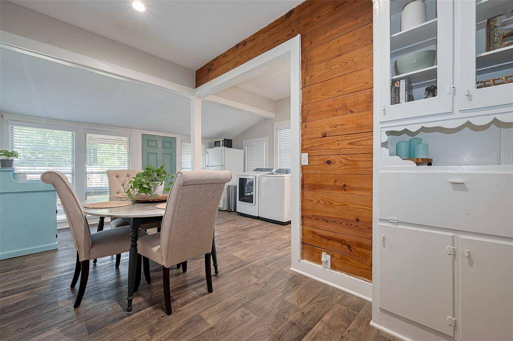 This inviting space features a cozy dining area with a rustic wood accent wall and built-in cabinetry. Large windows fill the room with natural light, creating a warm and welcoming atmosphere.