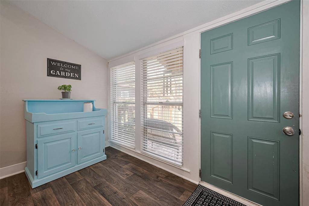 This area features a charming teal back door and large windows with blinds. Wood-look flooring adds warmth, creating a cozy and inviting atmosphere.