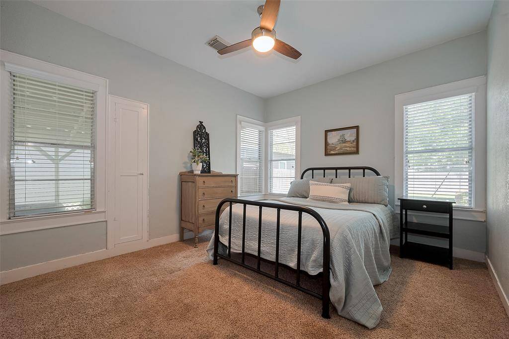 Spacious bedroom with large windows that fill the room with natural light, complemented by a striking wood panel accent wall for added charm.