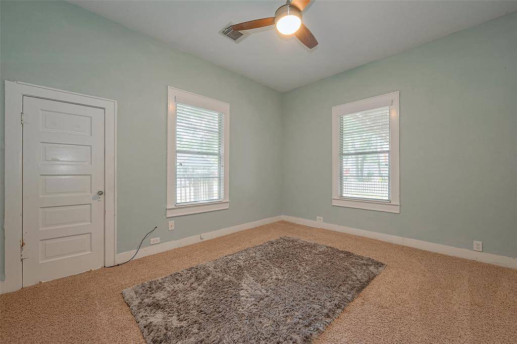 This extra room at the front of the house, just off the wood-paneled hallway, is filled with natural light from plenty of windows. A ceiling fan adds comfort to the space, which could be used as a bedroom, study, or more.