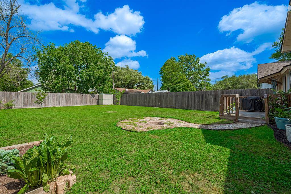 The spacious backyard features a charming wooden deck, ideal for outdoor dining, relaxation, or entertaining, with plenty of room to enjoy the outdoors in comfort.