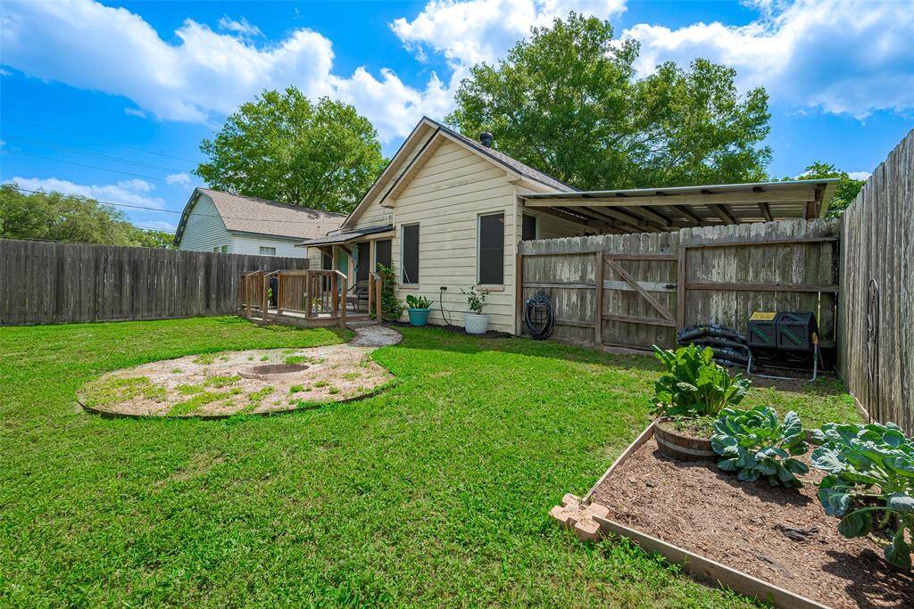 The spacious backyard features a charming wooden deck and fire pit area ideal for outdoor dining, relaxation, or entertaining, with plenty of room to enjoy the outdoors in comfort.