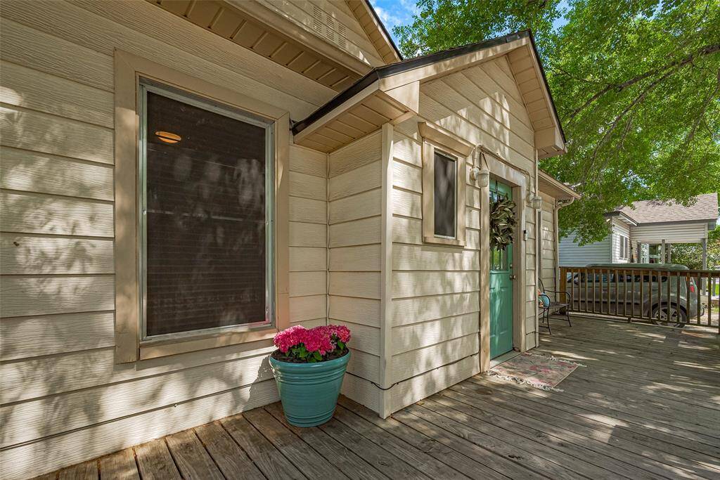 Charming front porch with a welcoming front door and a cozy seating area. The wood deck is shaded by trees creating a serene outdoor space. Perfect for relaxation or entertaining.