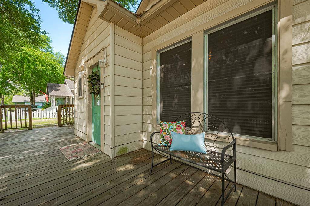 Charming front porch! The spacious wooden deck is perfect for relaxing, surrounded by lush greenery and a peaceful neighborhood.